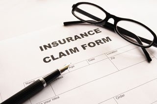 Eyeglasses and a pen resting atop an insurance claim form