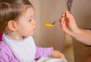 A baby being offered a spoonful of food