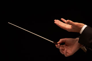 A close-up of a conductor's hands and baton