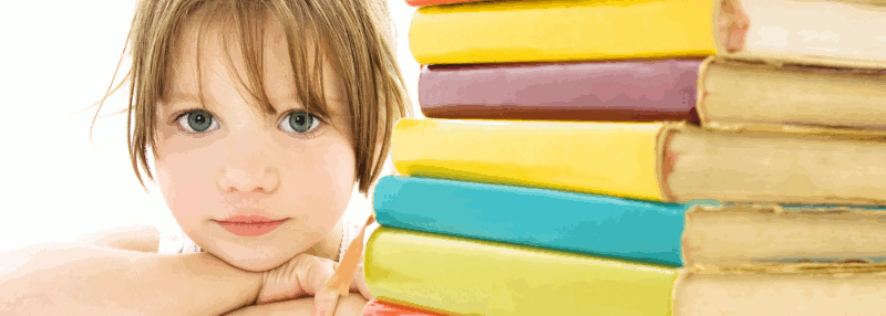 A young girl rests her chin on crossed arms beside a stack of text books