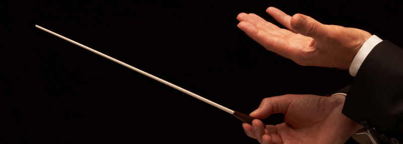 A close-up of a conductor's hands and baton